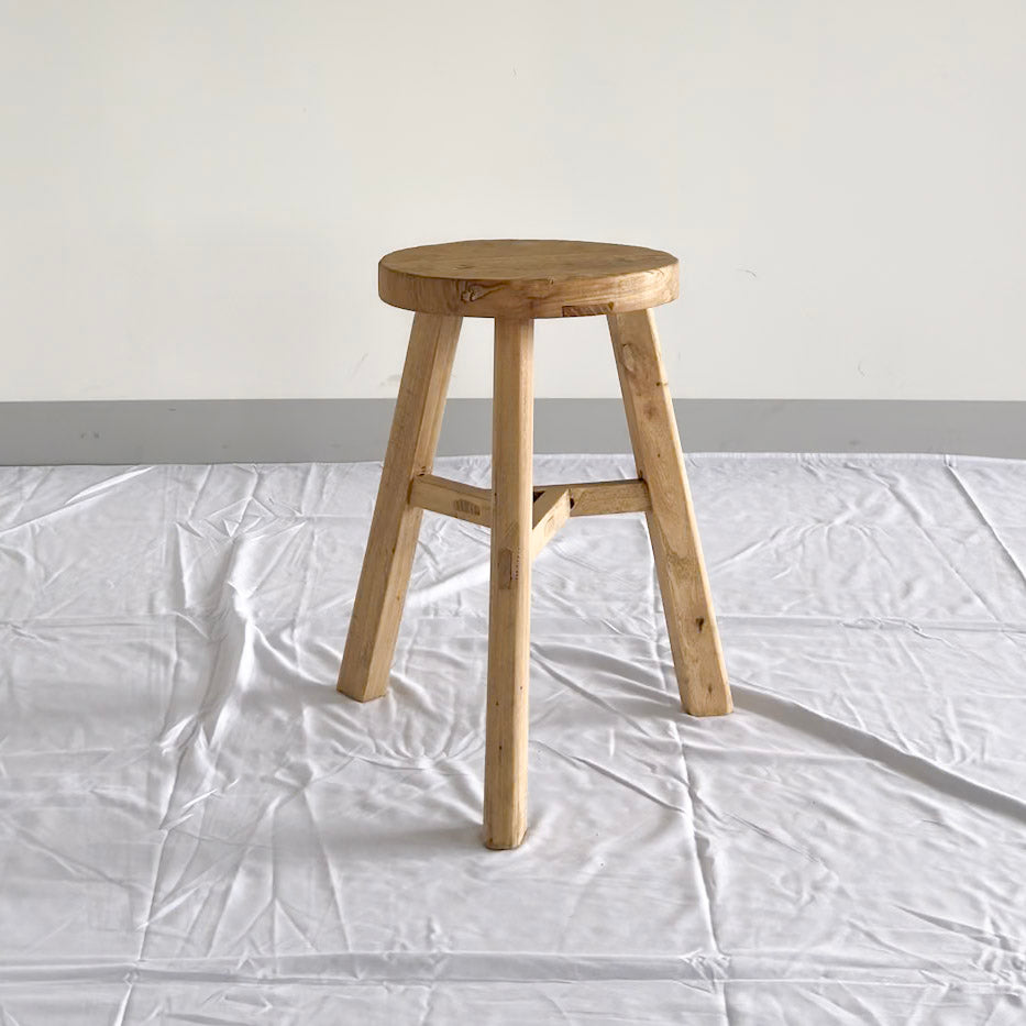 Wooden stool on a white floor with a plain background