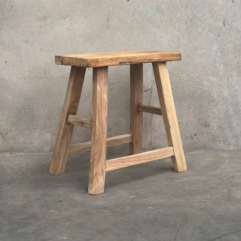 Wooden stool against a concrete wall